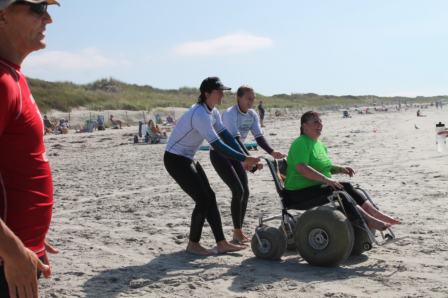 AmpSurf volunteers leading Tina Pedersen, a.k.a. "Miss Wheelchair RI", to the water's edge to prepare for an unforgettable surfing experience.